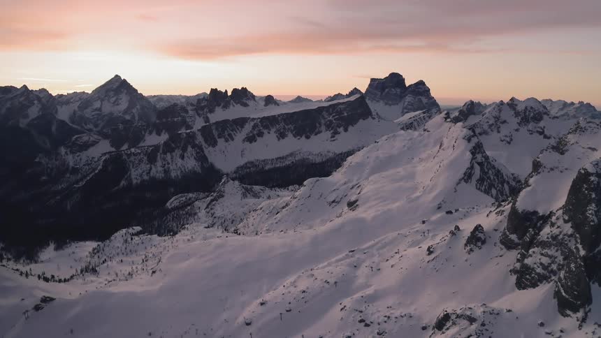 Aerial view of snow covered peaks of a mountain range at sunset