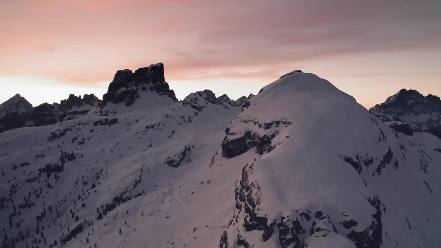 Aerial view of snow covered peaks in a mountain range at sunset