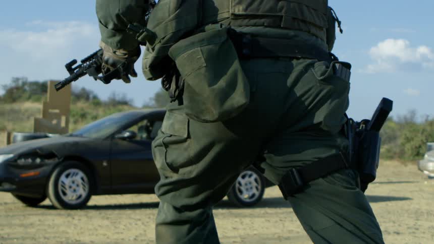 An armed soldier runs towards a vehicle during a training session