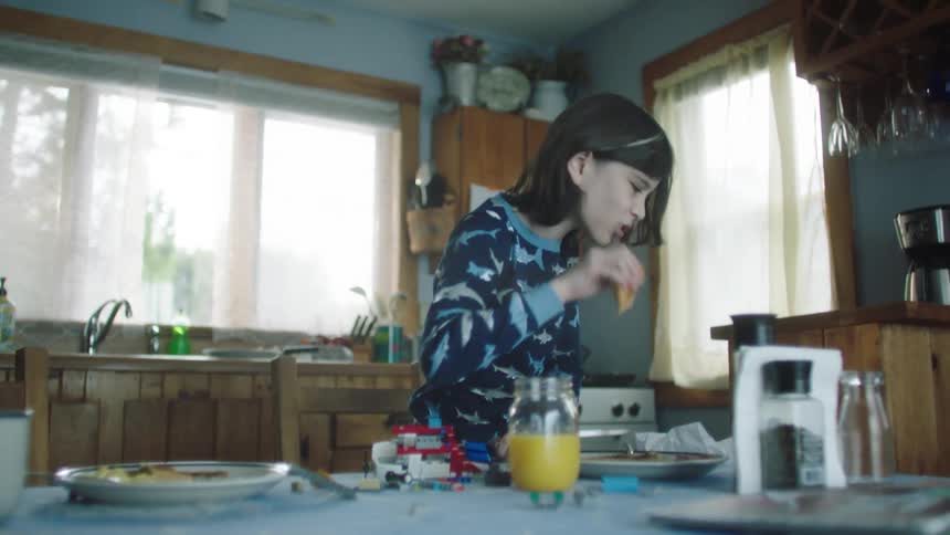 Girl eating breakfast in the kitchen on pajamas stands up and runs away