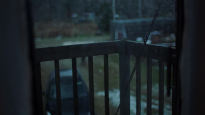 A view from outside a home window of a child running through a yard in the rain
