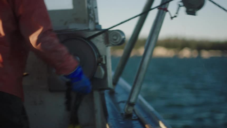 A boater pulls a boat fender up from the ocean