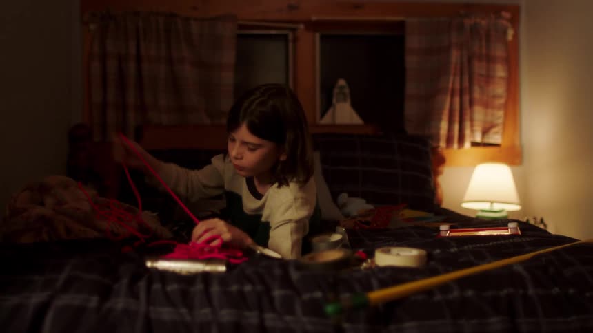Girls lies on bed unraveling pink cord