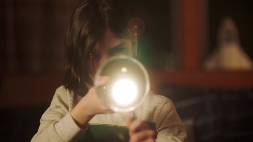 A girl inquisitively shines a flashpoint through a magnifying glass