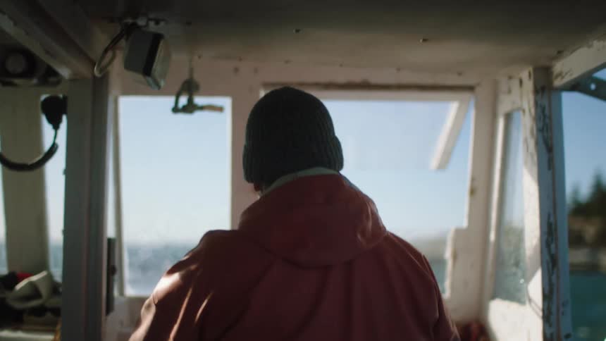 An elderly man drives a boat
