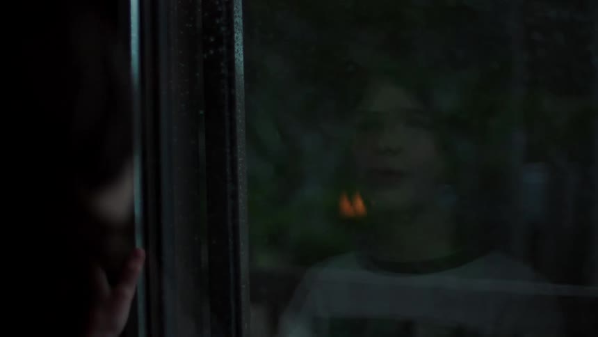 A teenage boy looks at his reflection in a window
