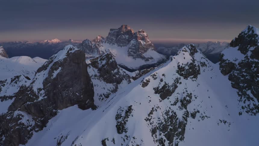 Snow capped mountain ridges under a dim sky