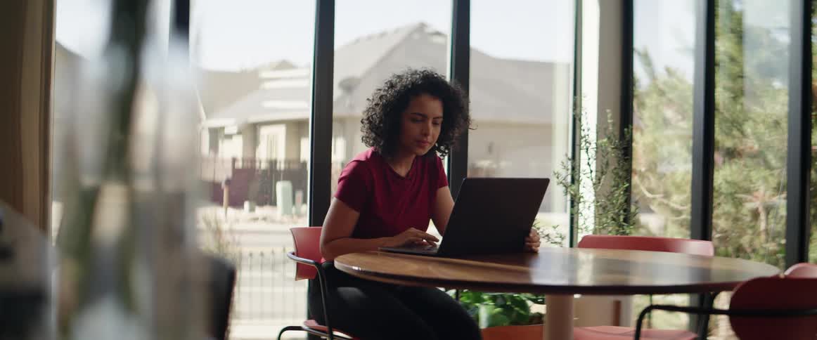 Woman sitting on desk in office working on laptop