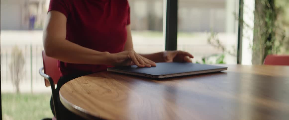 Young woman sits down on a table in an office and opens a laptop