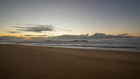 Ocean waves wash ashore at sunrise