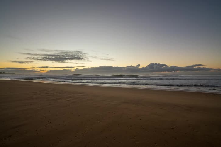 Ocean waves wash ashore at sunrise