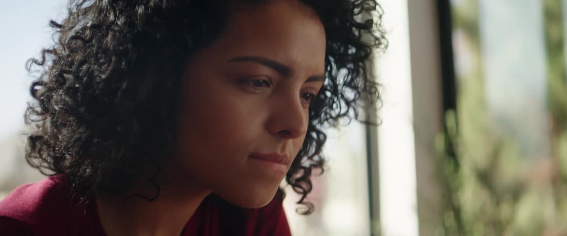 A woman is looking over something by the window