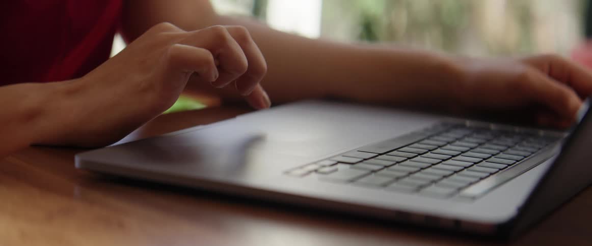 A female student sits at a table and works on her laptop
