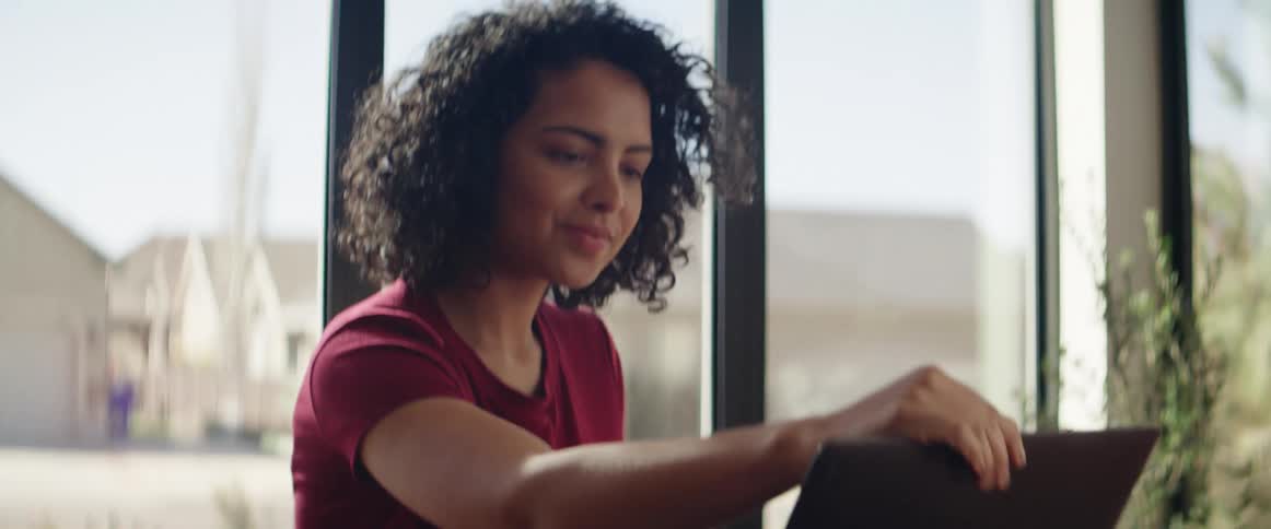 A teenager sits down at a table with her laptop