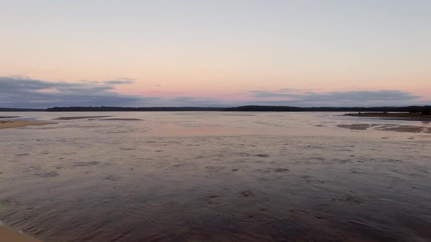 Water flows near shoreline at dusk