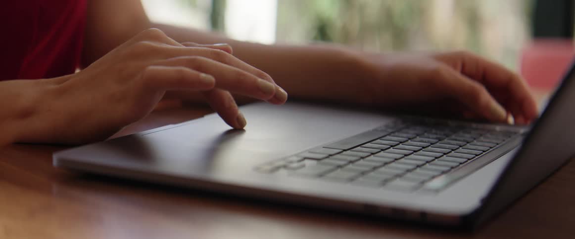Woman sitting at table works on laptop