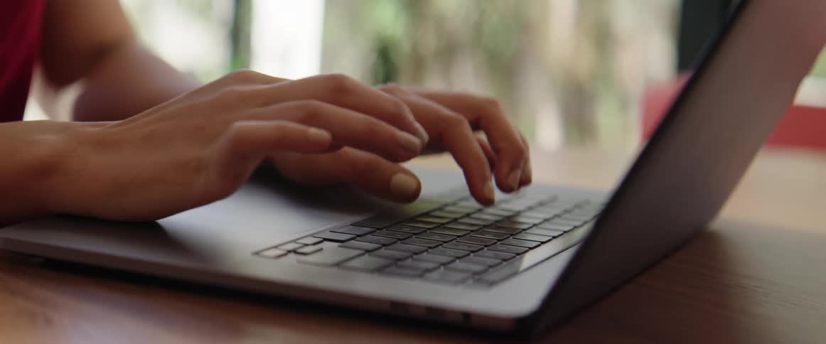 Fingers typing on a laptop indoors
