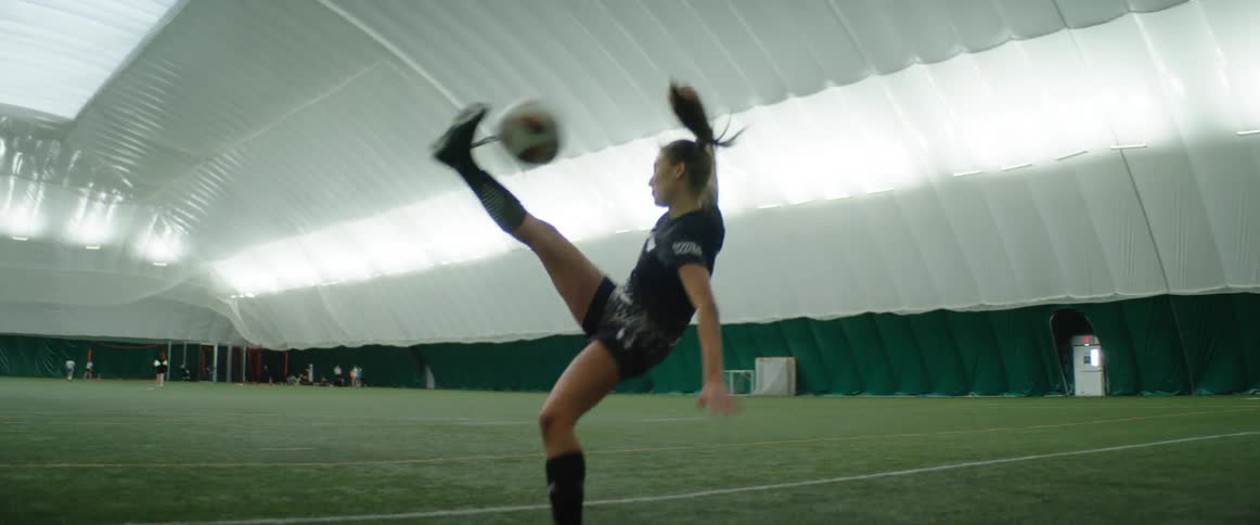 A woman is kicking a soccer ball