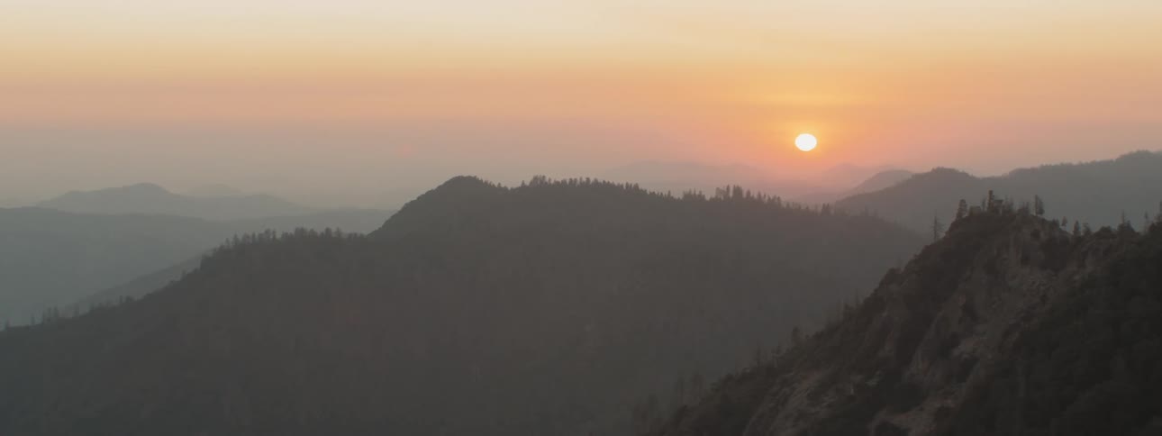Mountain range covered in fog at sunset under a red sky