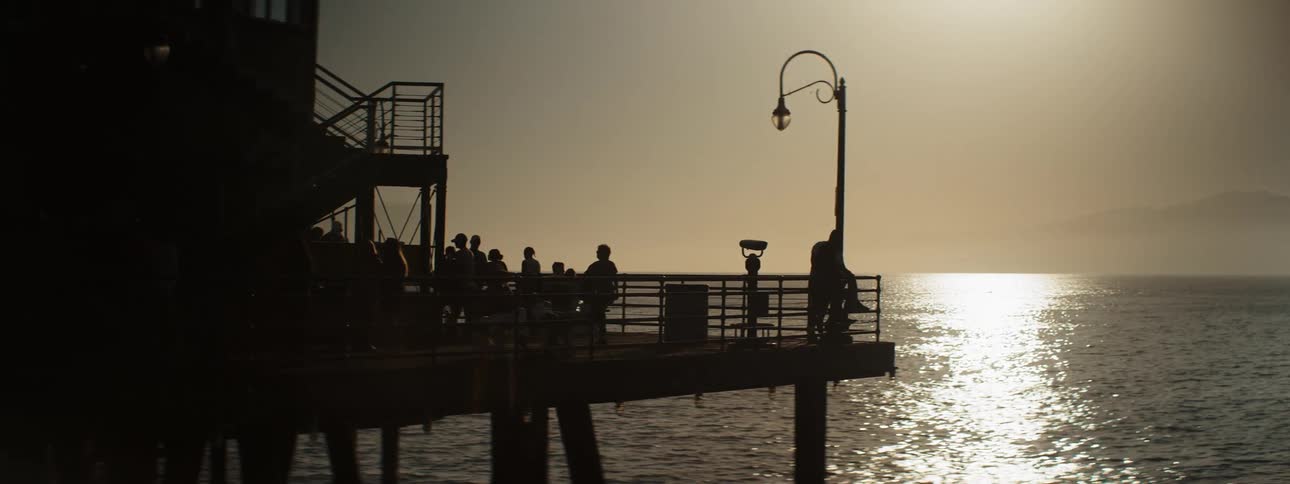 Tourists on two story pier overlooking ocean in silhouette
