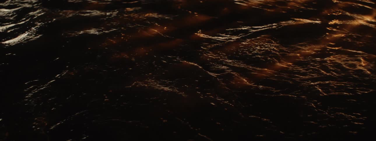 Surf rushes in and out as light casts parallel shadow across water surface
