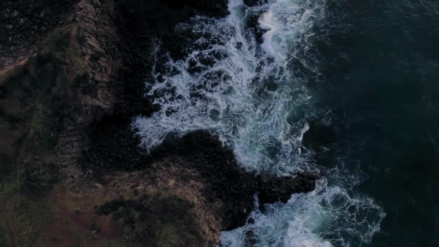 Aerial view of waves hitting the side of a cliff