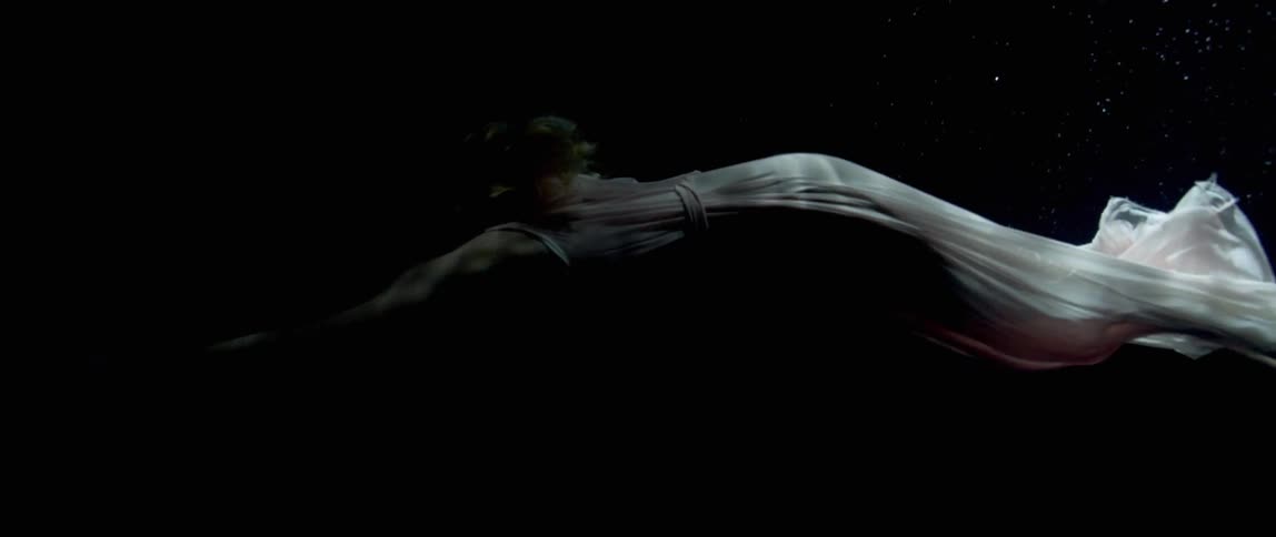 A white woman in a white dress swims underwater