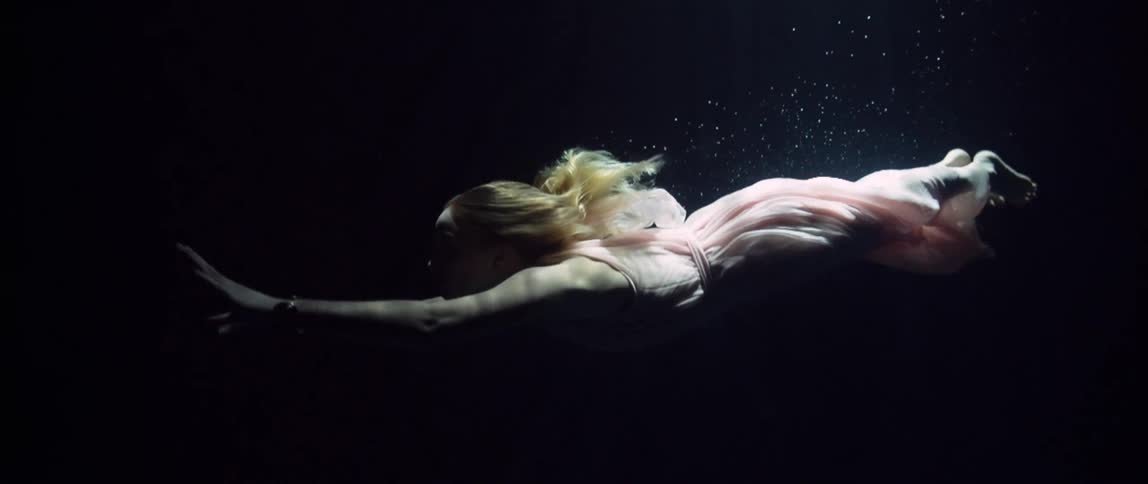 A white woman in a dress swims underwater