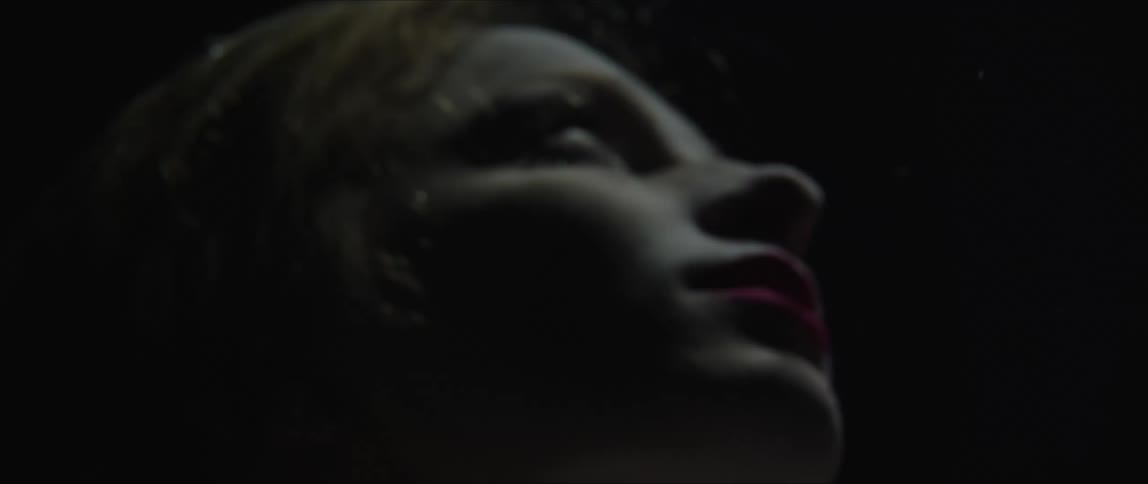 Woman floating underwater with surface light reflecting in her face
