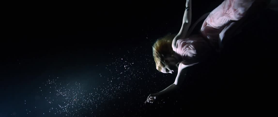 Woman wearing a pink dress dances while floating underwater
