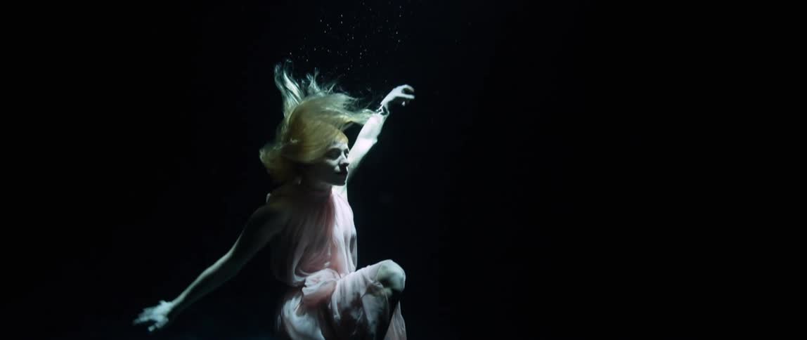 Model swims underwater in pink evening gown