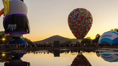 A festival has many hot air balloons at sunset