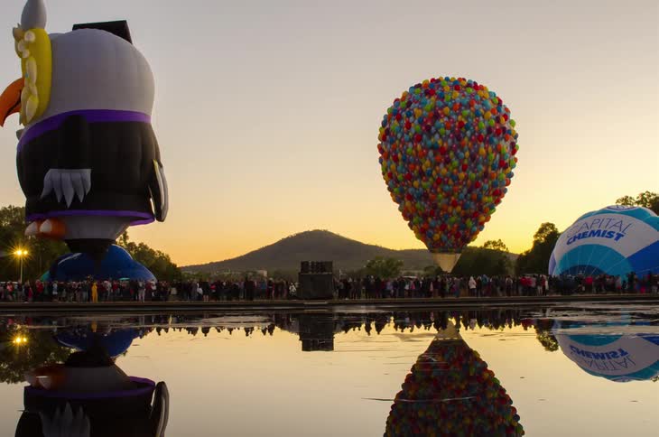 A festival has many hot air balloons at sunset