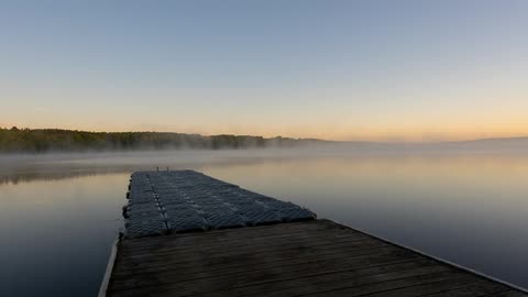 Clouds float over a dock and lake