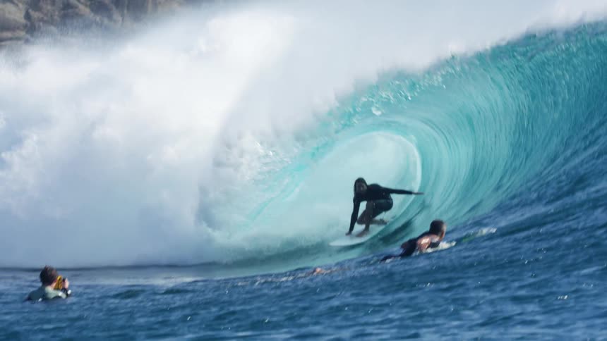 A male surfer rides on a big wave in the sea using a surfboard
