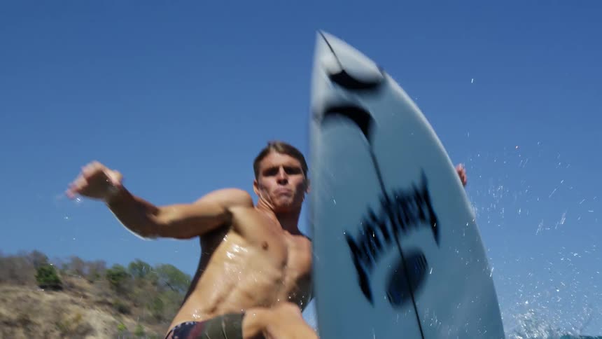 A white man surfs a waves and then jumps the board into the air