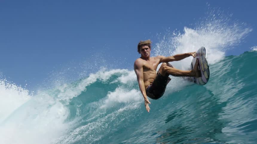Surfer rides large wave on board falling as it crashes