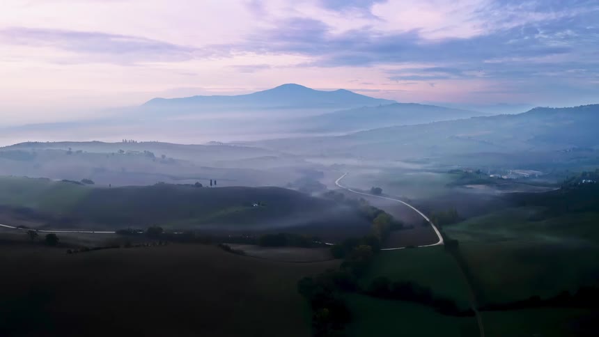 A road snakes through fields and farmland in a rural area