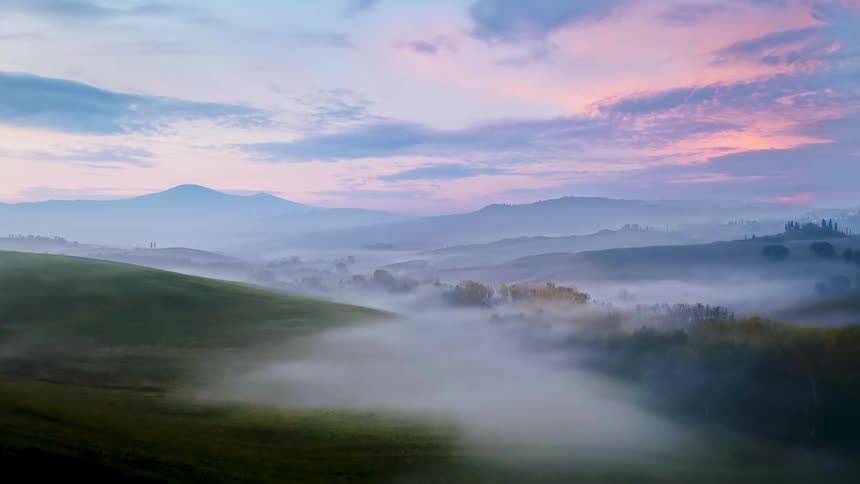 Aerial view of hills covered in fog at sunset