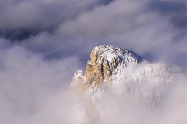 Timelapse of clouds moving around a snow covered mountain peak