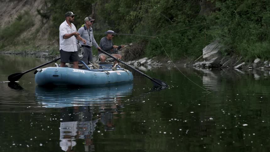 Three white guys fish while on a boat on a lake