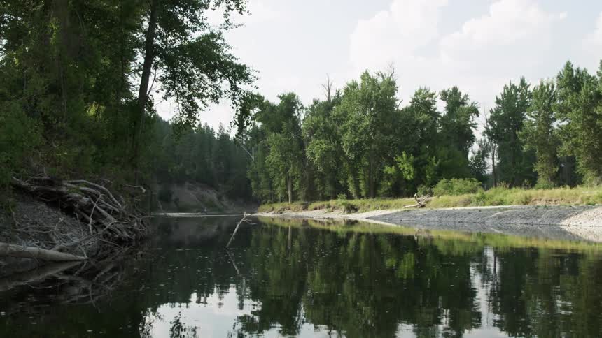 A lake with a placid surface reflects the surrounding trees along the coastline