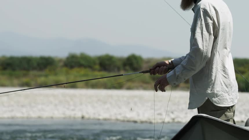 An elderly man standing in a boat fishing