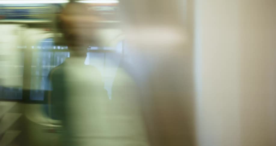 A subway train carrying passengers travels past a platform where others are waiting