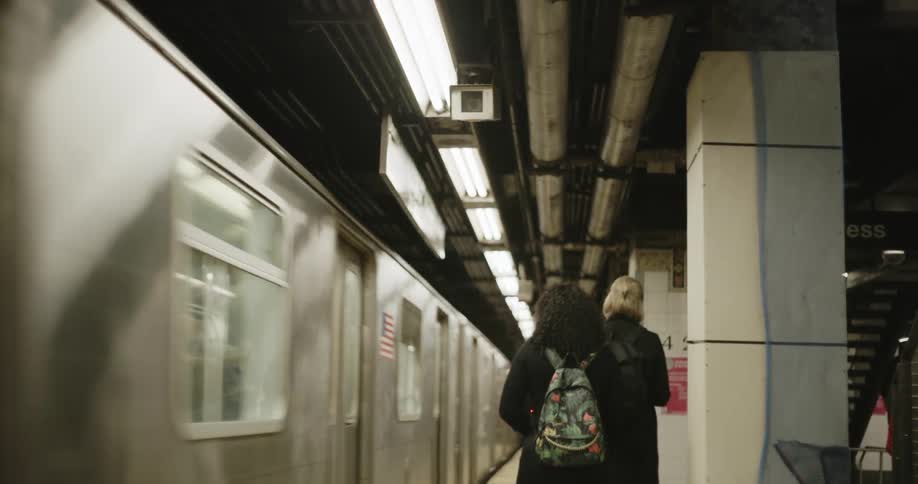 Men and woman walk on the platform as a subway train travels by