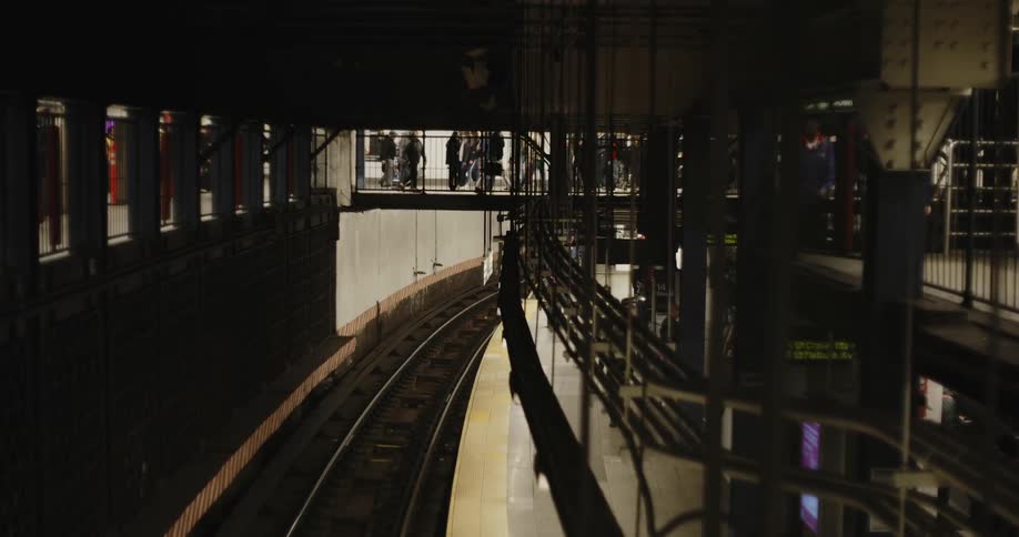 People walking in a station as a train drives through