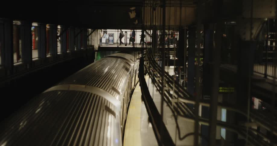 A train pulling in to a station as people walk by