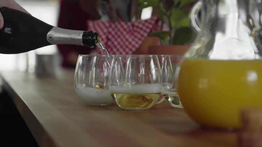 Person pours champagne from a bottle into glasses on a table