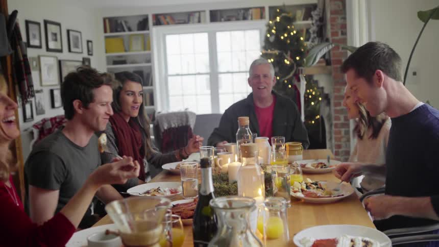Family gathered around the table laughing and enjoying christmas brunch