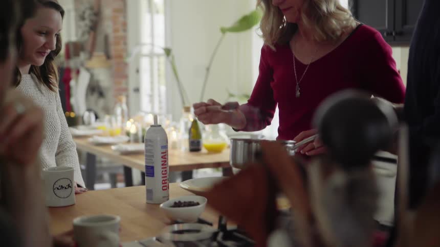 A white woman spoons out food onto a plate while others watch